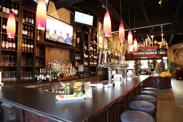 Custom Symposium Cafe bar interior with a dramatic wine wall, dark woodwork and upscale lounge design.