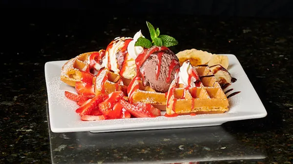 Strawberry chocolate dessert waffle with fresh berries, ice cream and rich chocolate drizzle at Symposium Cafe.