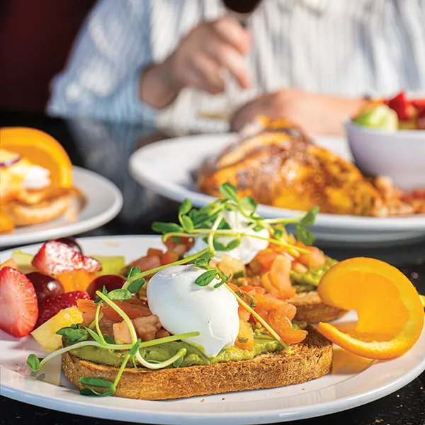 Waterloo Ontario brunch spot serving avocado toast with poached eggs, smoked salmon and fresh fruit at Symposium Cafe.
