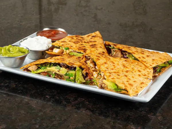Popular appetizer in Bolton Ontario featuring chicken quesadilla with guacamole, salsa and sour cream at Symposium Cafe